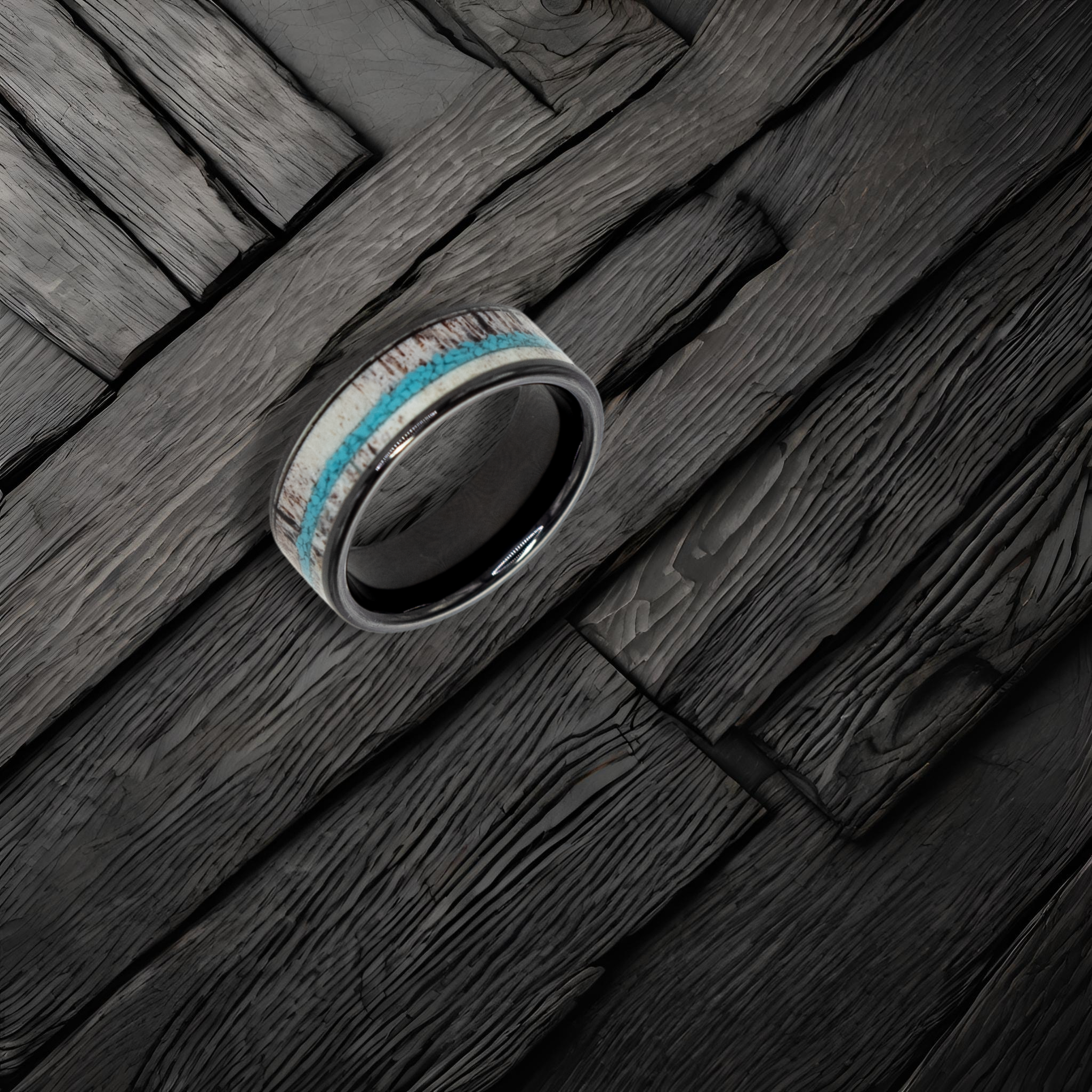 Hermes ring – Polished Black Ceramic with Turquoise and Deer Antler Inlays from the Hustler Collection. Lifestyle shot, placed on textured wood.