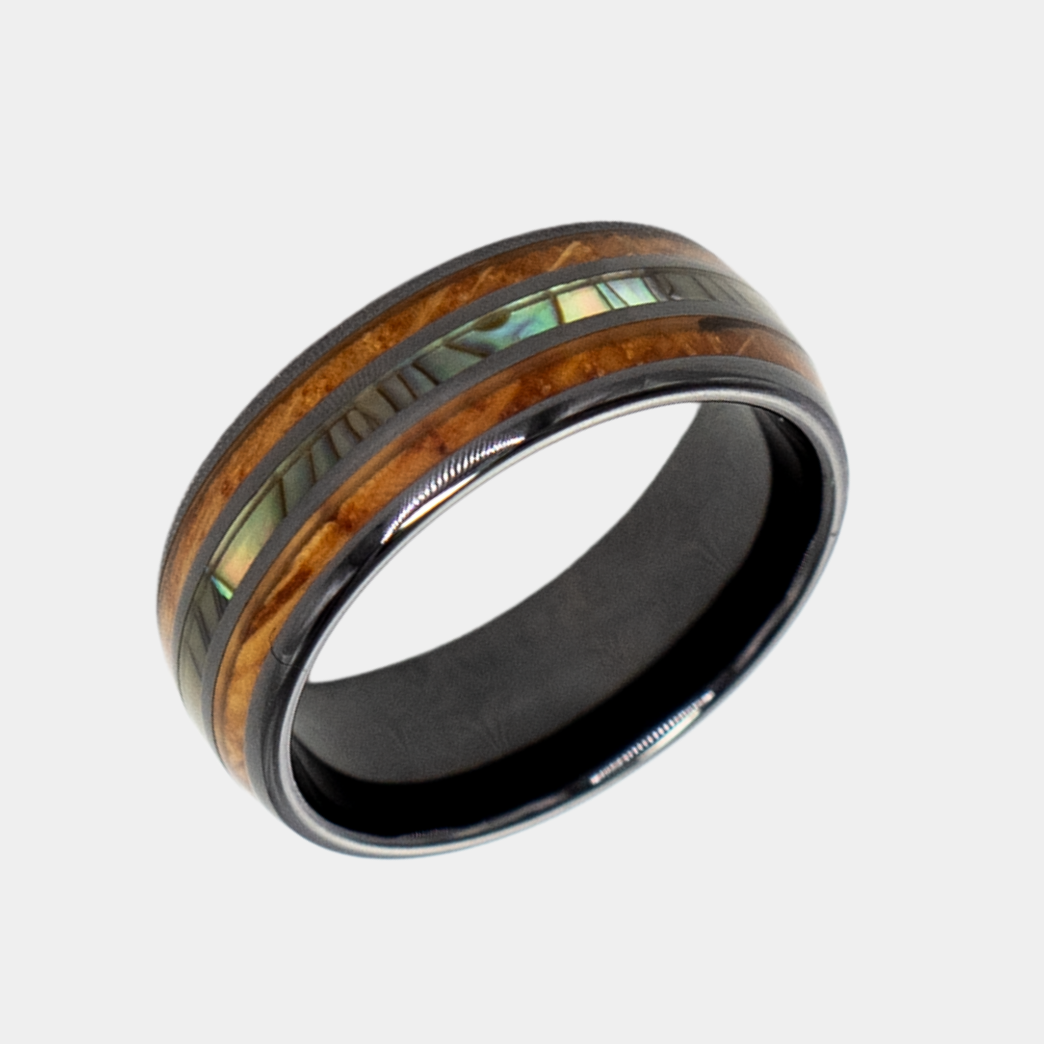 Odysseus ring – Polished Black Ceramic, Featuring a Double Whiskey Barrel Wood Inlay and Abalone Shell Inlay from the Hustler Collection. Angled view highlighting shape and finish.