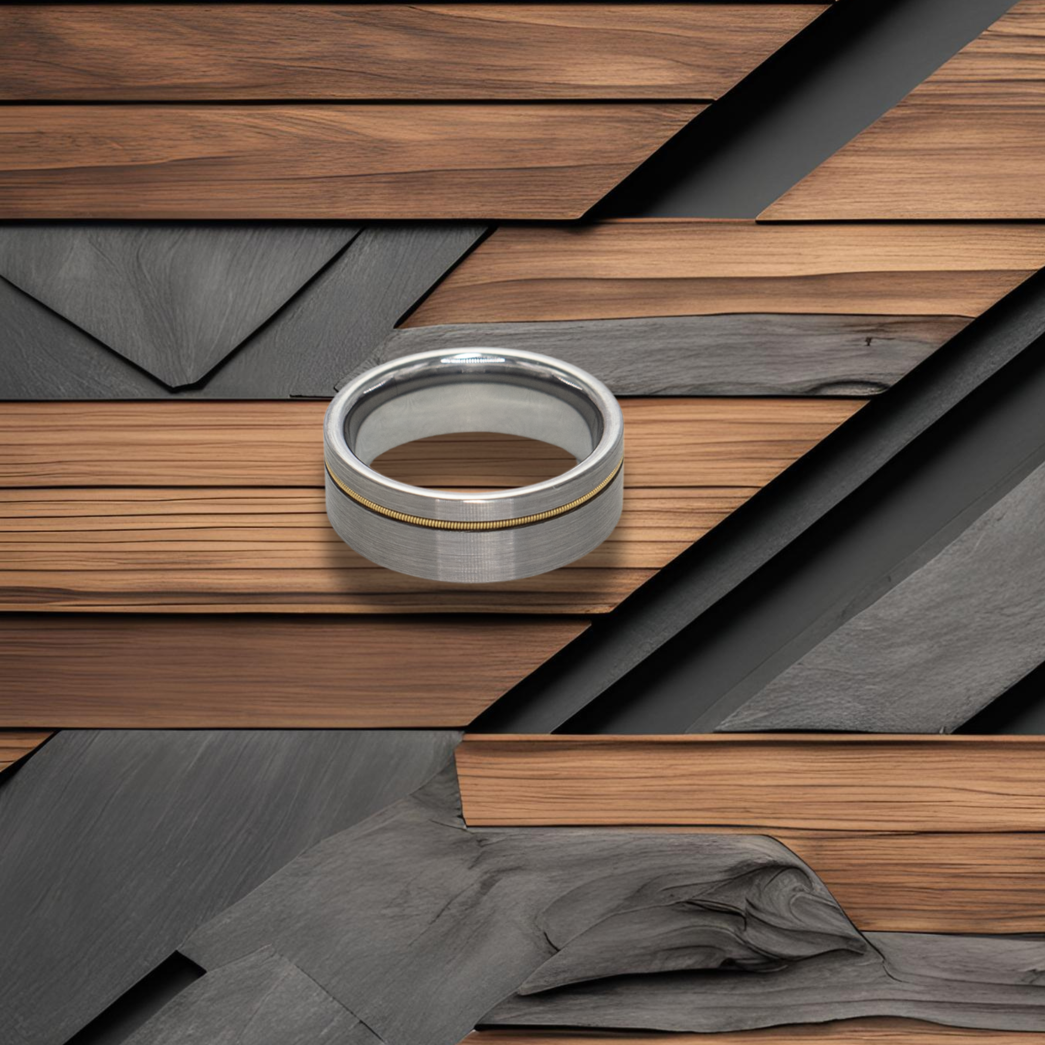 Orpheus ring – Brushed Silver Tungsten with Gold Guitar String Inlay from The Hustler Collection. Lifestyle shot, placed on textured wood.