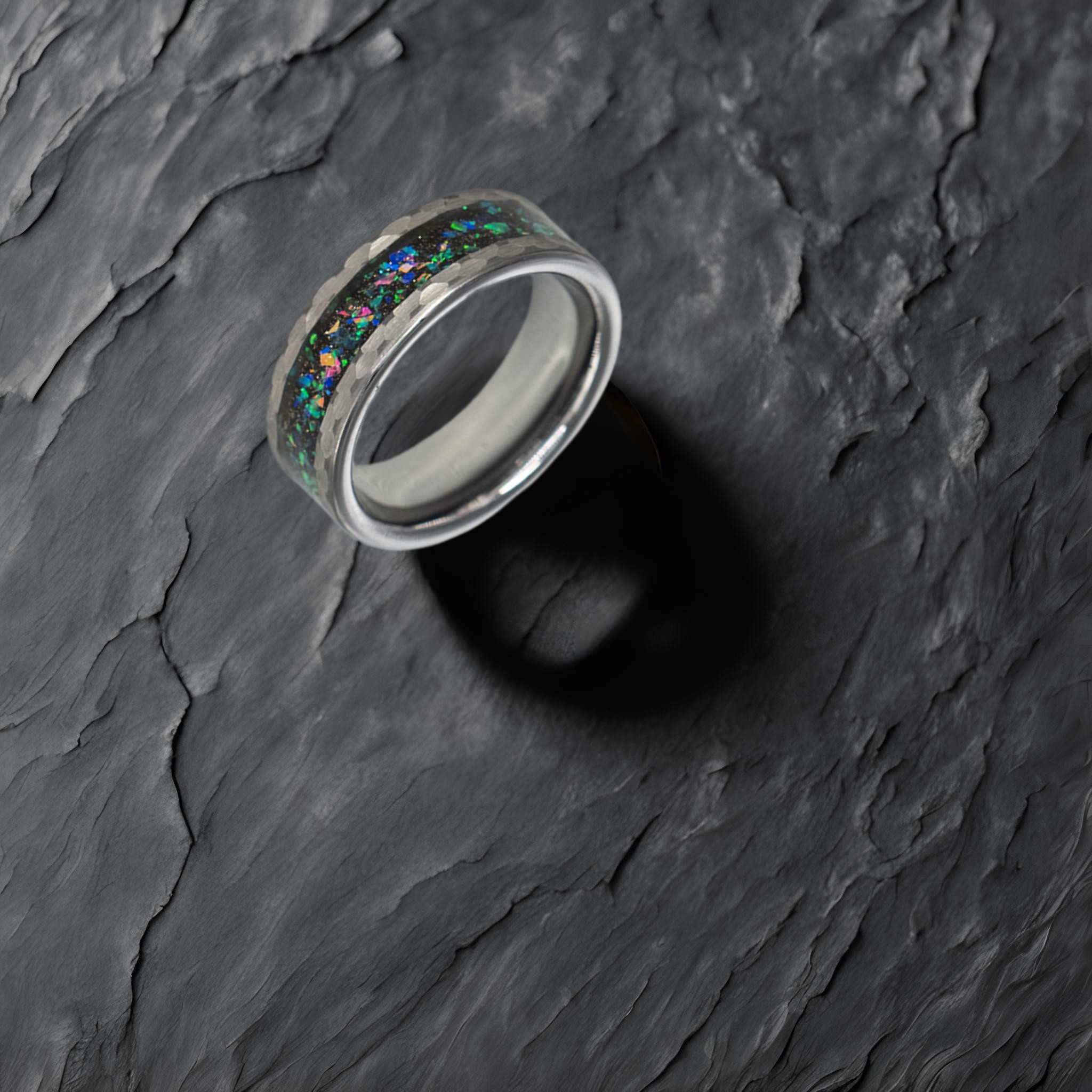 Typhon ring – Hammered Silver Tungsten featuring a Crushed Opal Inlay from the Hustler Collection. Lifestyle shot, placed on textured fabric.