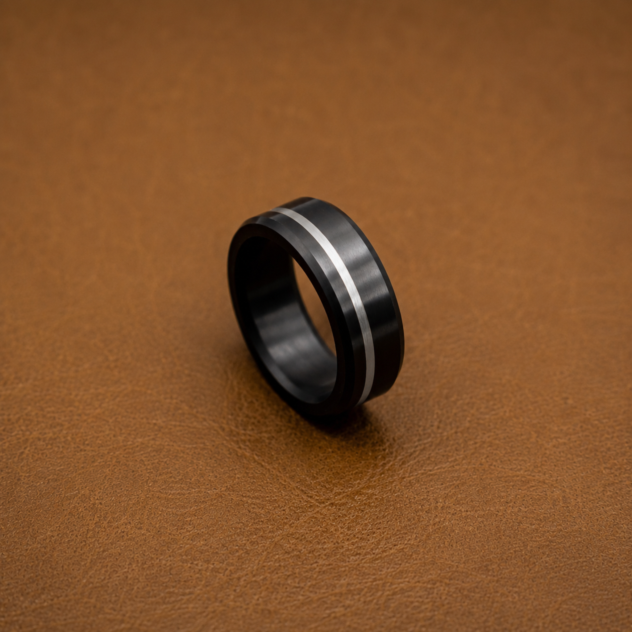 A Solid Black Diamond wedding band with an offset silver inlay, displayed on a textured brown leather surface.