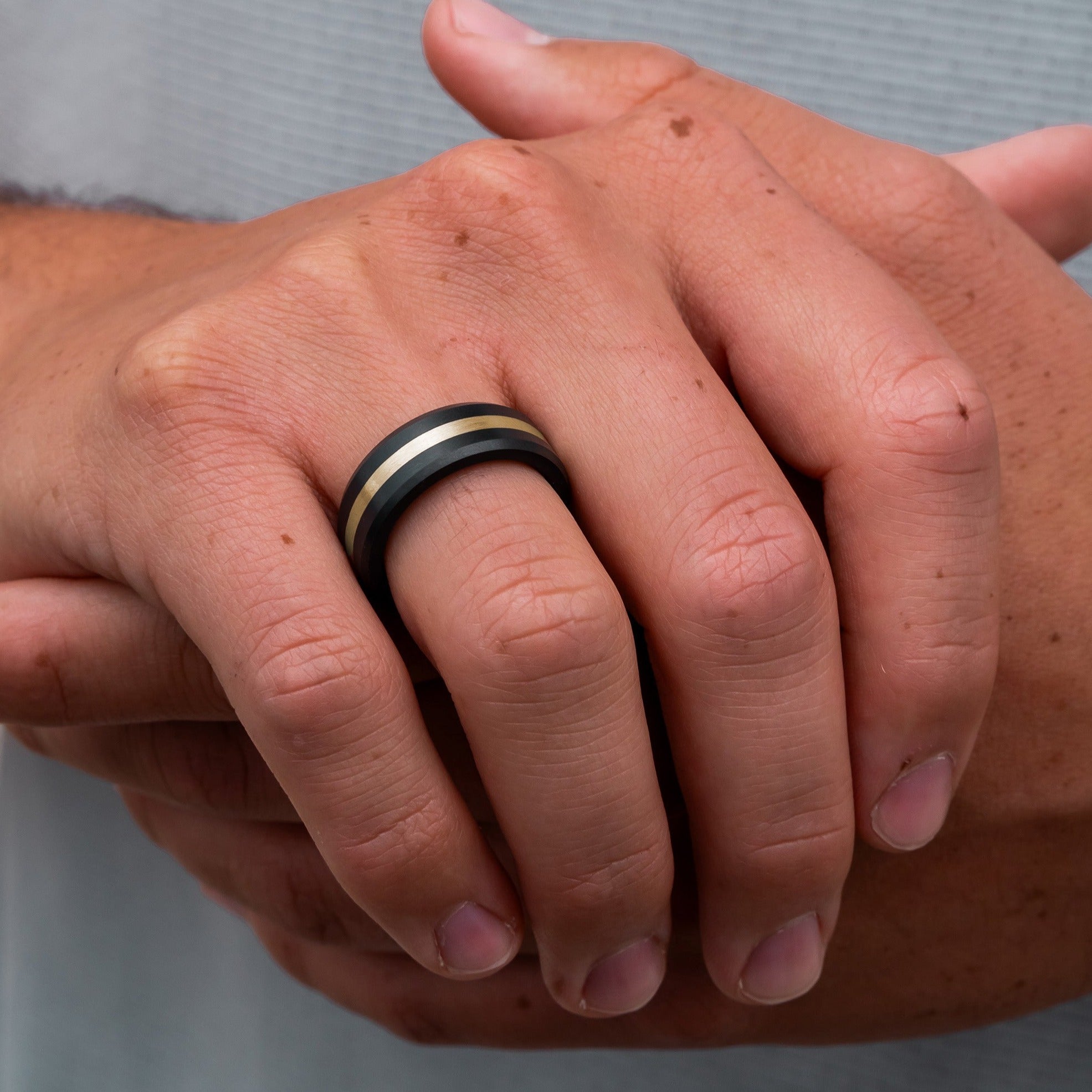 Lifestyle shot #3 of men's hands wearing our Elysium ARES Men's Black Diamond & 14k Yellow Gold Inlay | ElysiumBlack.com | Men’s 14k Yellow Gold Inlay Wedding Rings