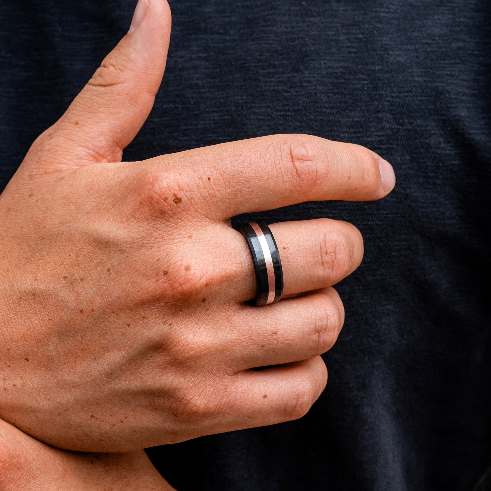 Lifestyle shot #1 of men's hands wearing our Elysium ARES Men's Black Diamond & 18k Rose Gold Inlay | ElysiumBlack.com | Men’s 18k Rose Gold Inlay Wedding Rings