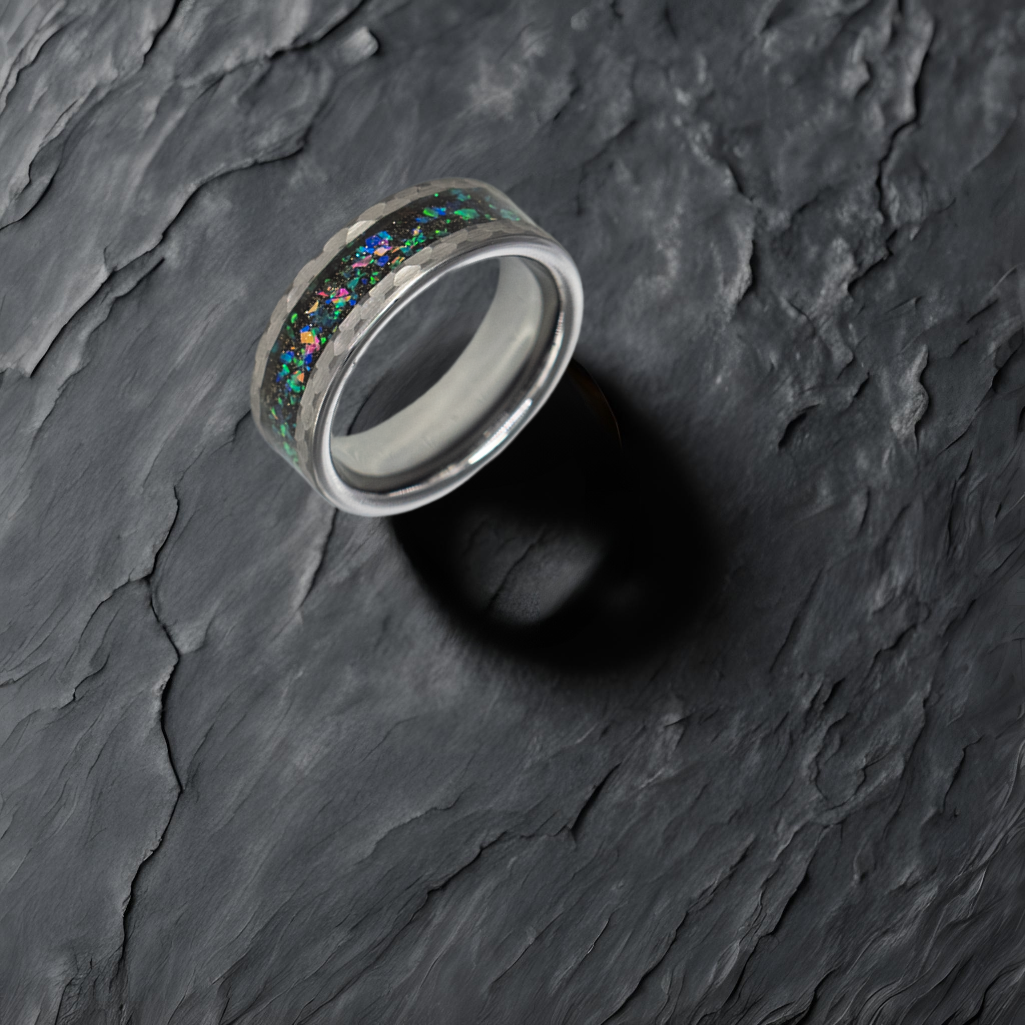 Typhon ring – solid black diamond with polished beveled edges from the Hustler Collection. Lifestyle shot, placed on textured fabric.